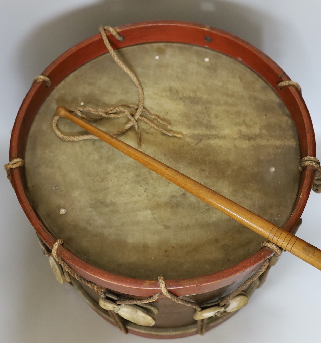 An elm and brass studded drum, with painted bands and a drum stick